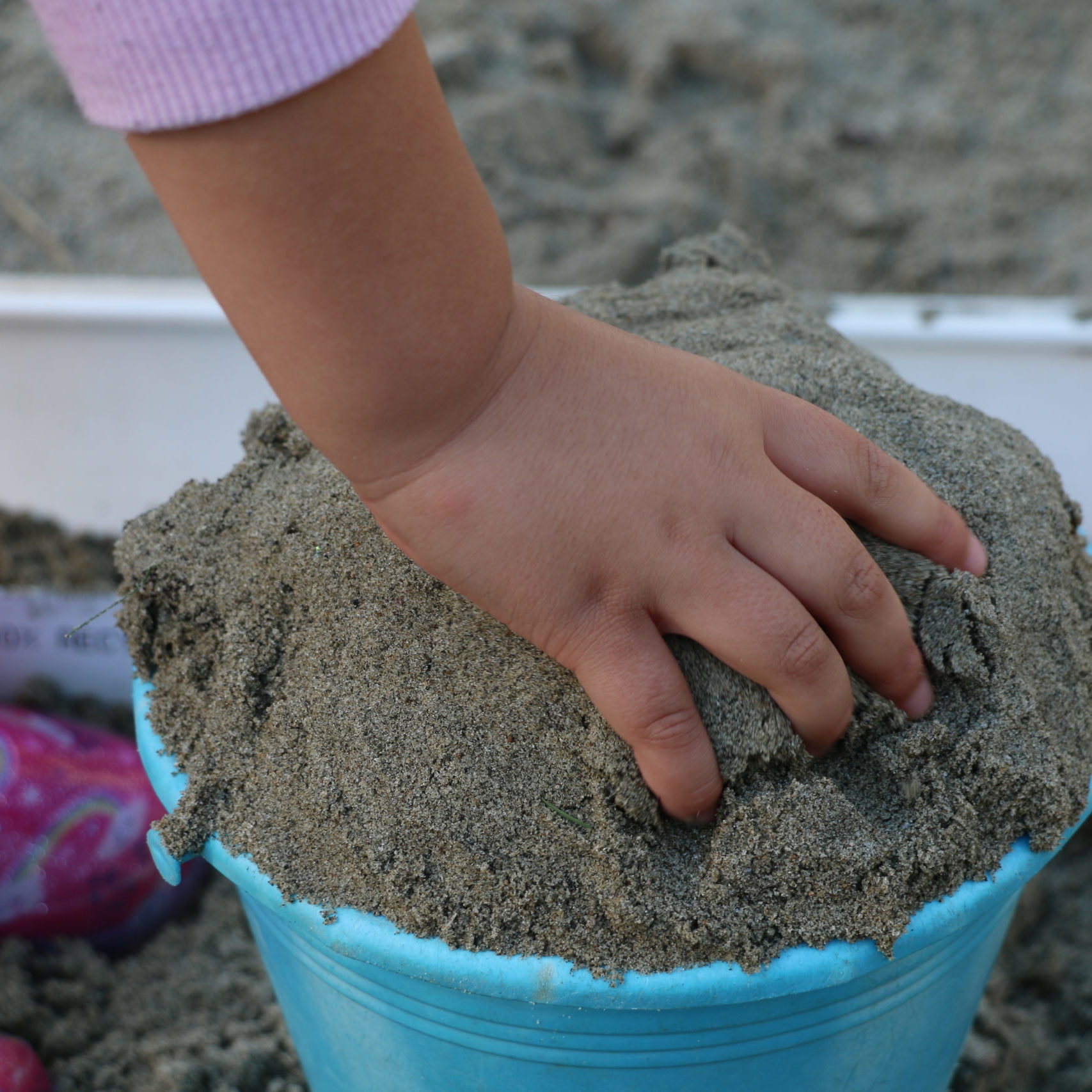Child playing with a bucket of sand