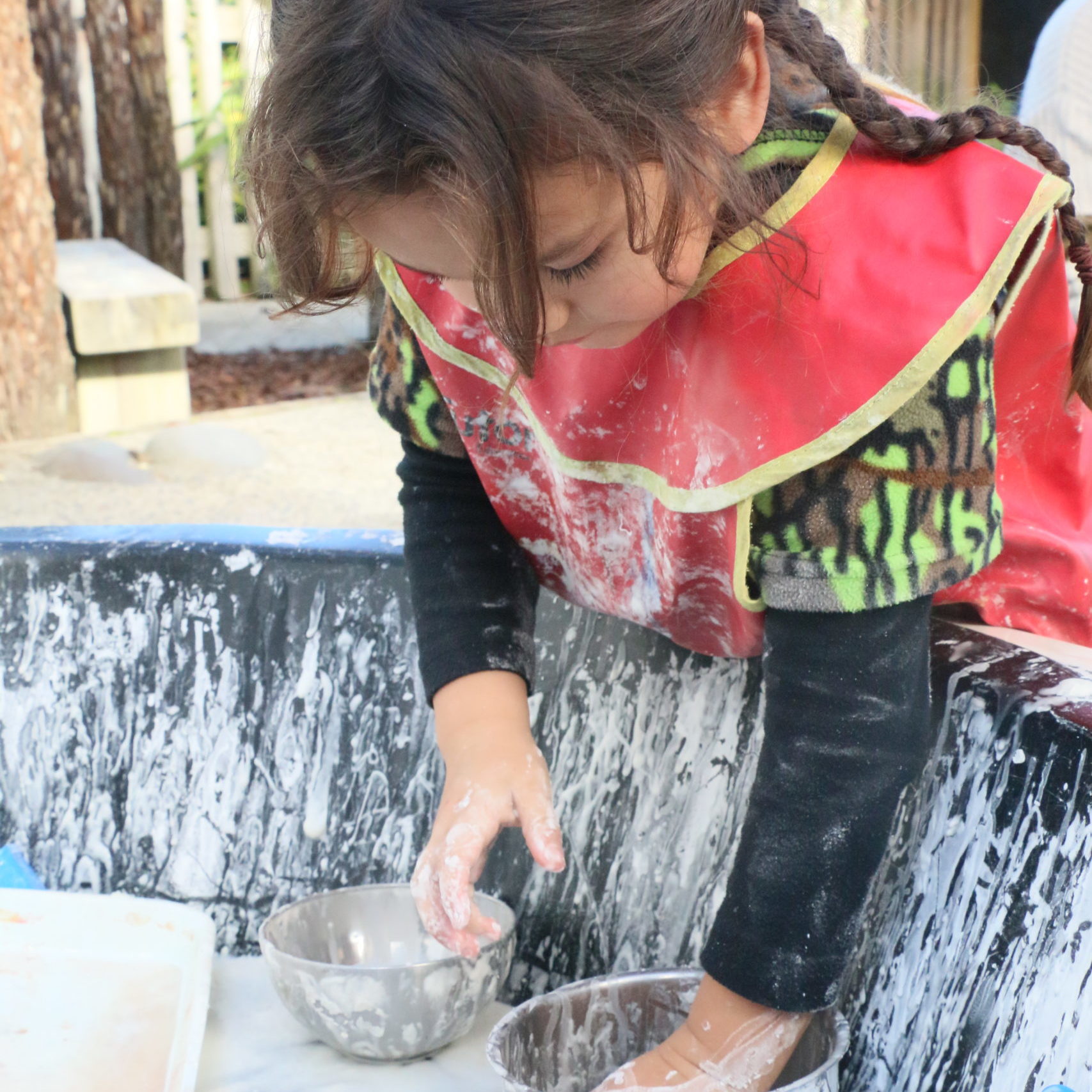 Child in apron playing with gloop