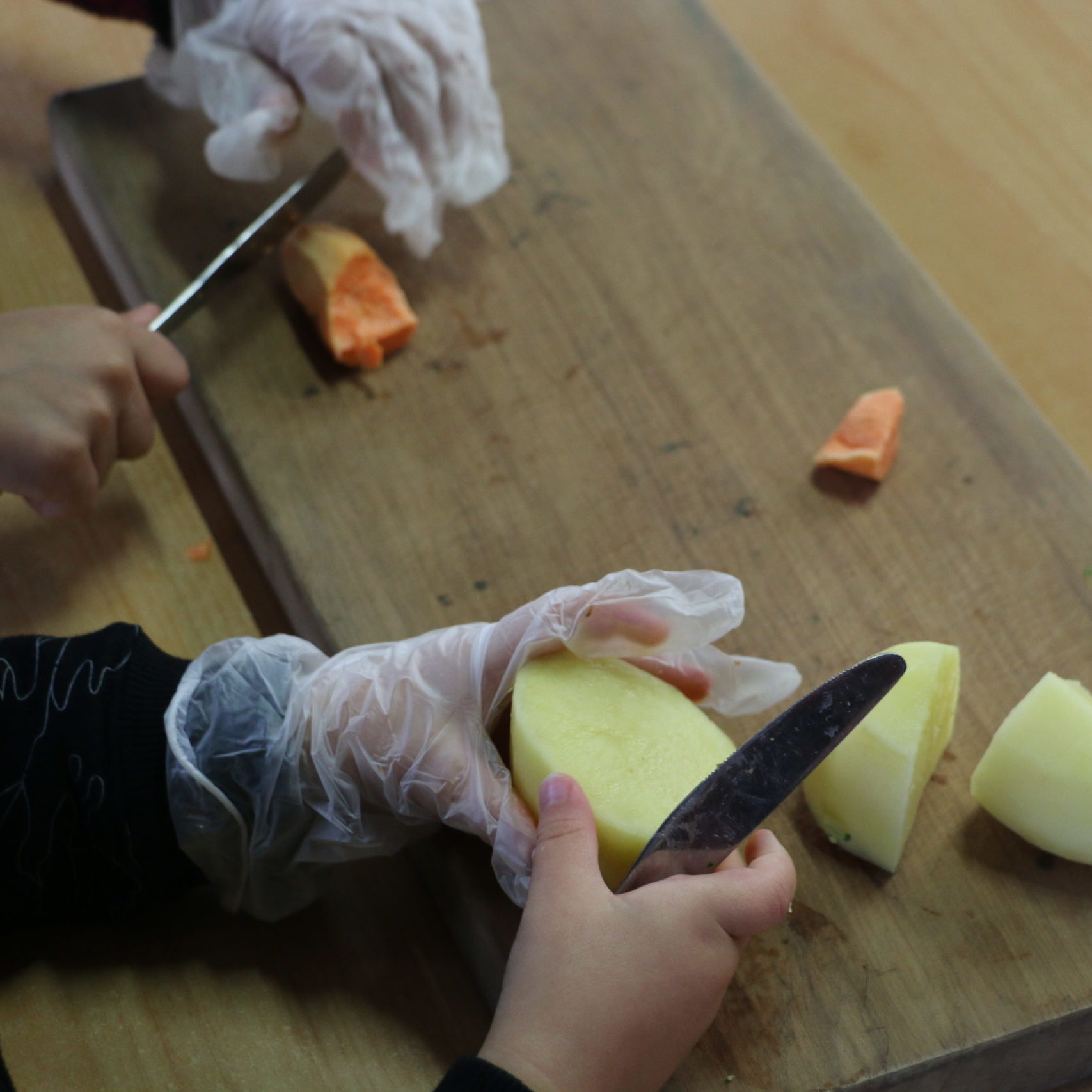 close up of children cutting vegetables
