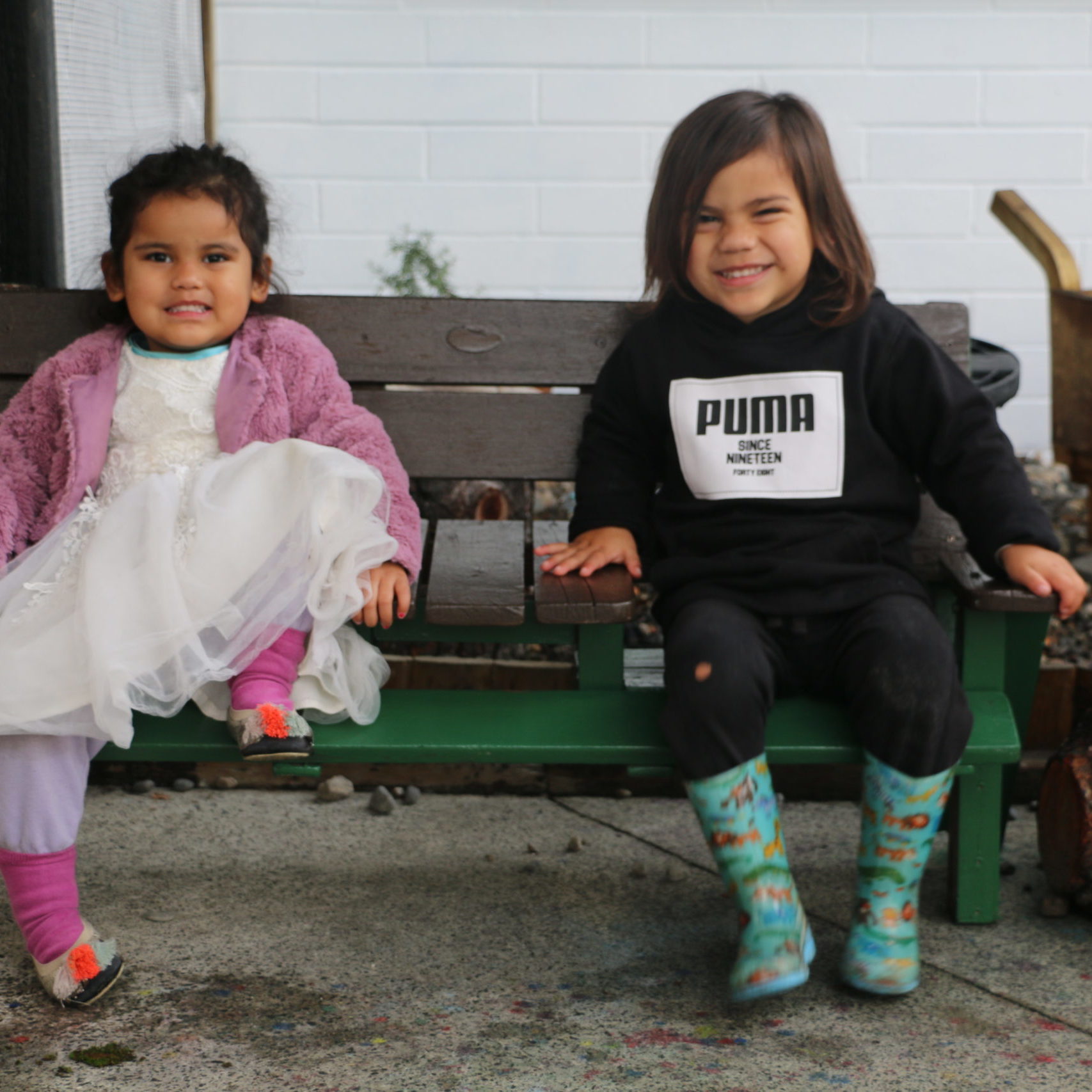 two children sitting on a bench laughing