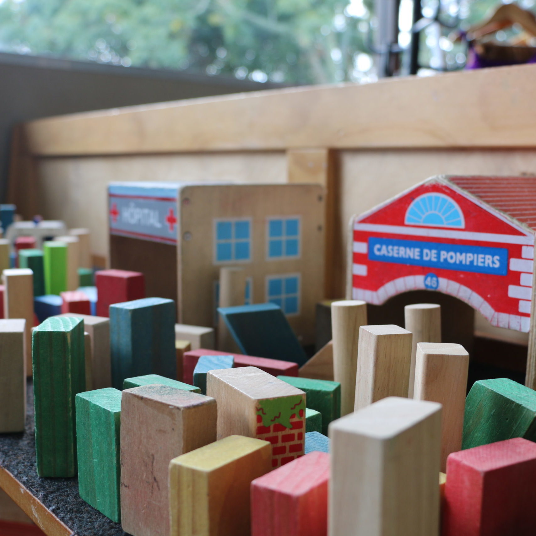 colourful blocks lined up on shelf with wooden houses