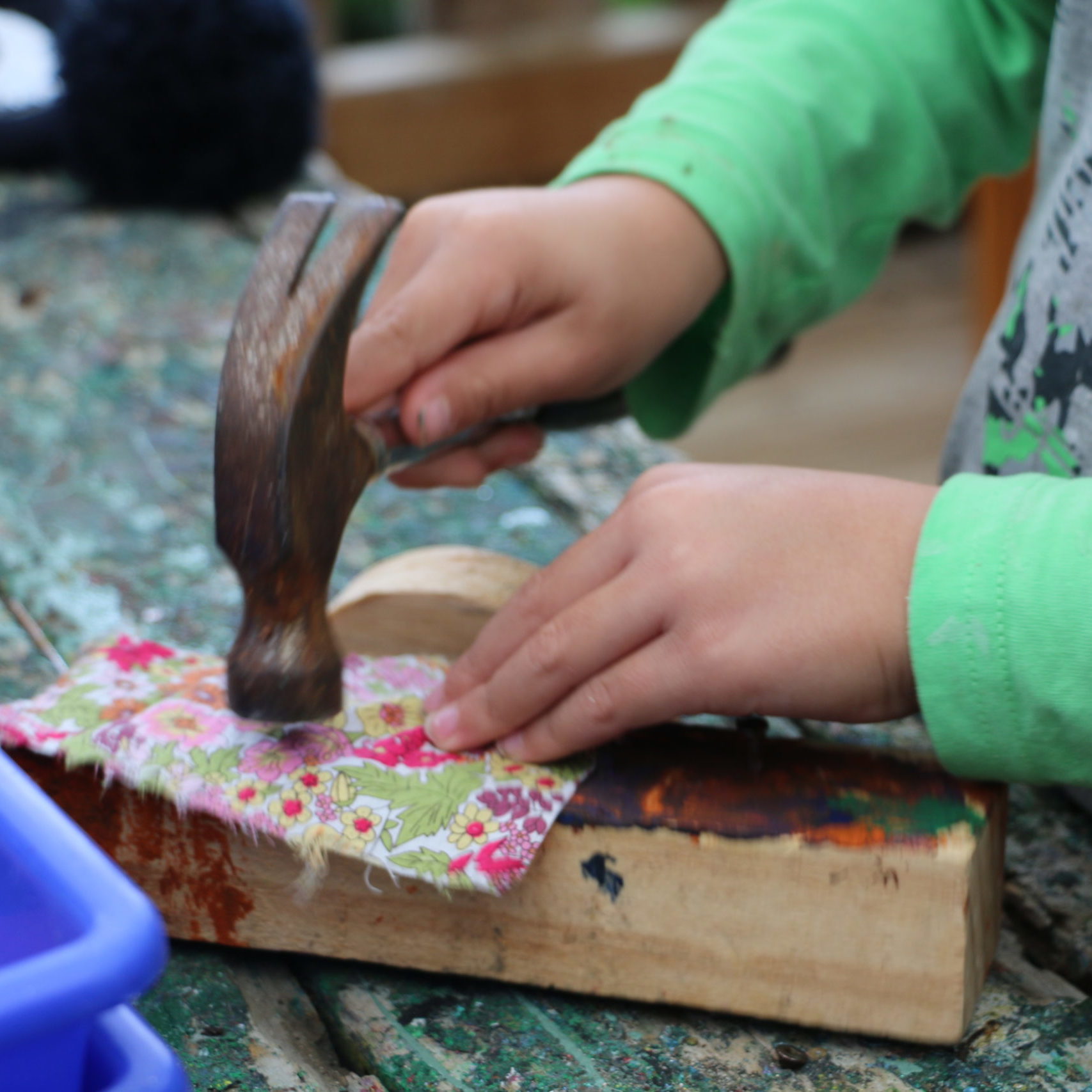 Child hammering nail onto piece of wood