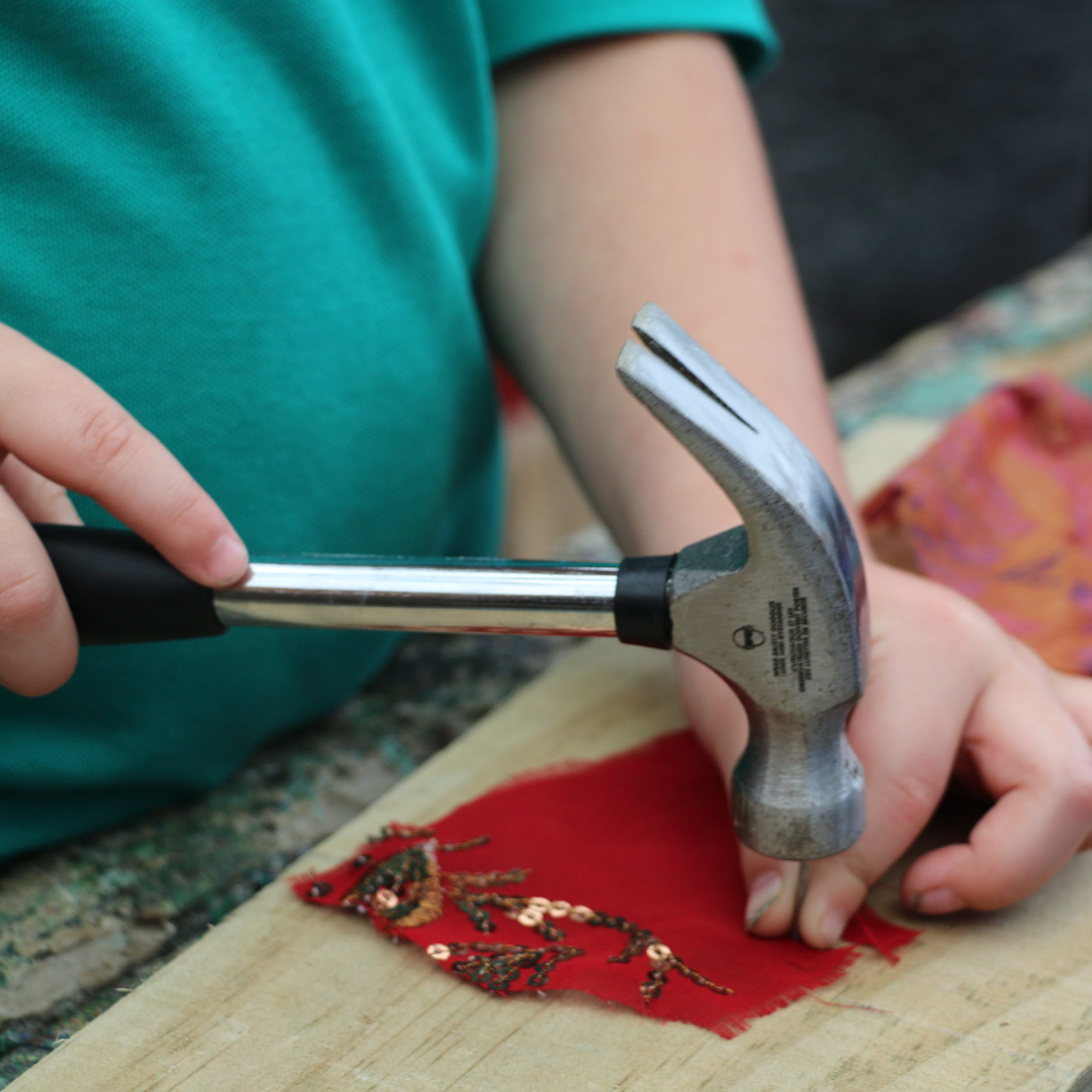 child hammering a nail onto piece of wood